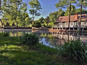 Ein Gebäude am Seeufer mit einem Steg, umgeben von Bäumen und ruhigem Wasser.