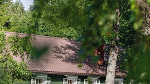 A green building with a stone foundation, a balcony, and a reflection in the water. - Scenic Riverside House with Beautiful Views (Litwinki)