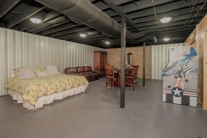 A room with a bed, a wooden cabinet, a dining table with chairs, and a large poster on the wall. - 🌲 70 Acre Mountain Farmstead 🏞️ Stocked Pond, Game Room & Seclusion (Sevierville)