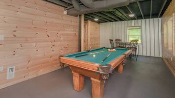 A pool table in a room with wooden walls and a window.