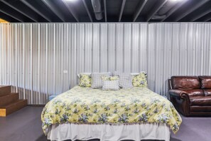 Un dormitorio con una cama, un sofá de cuero marrón y una escalera.