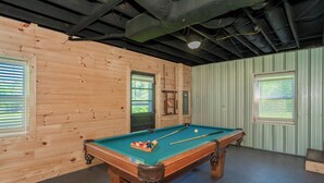 A pool table with balls, a cue stick, and a billiard rack in a room with wooden walls and a metal ceiling. - 🌲 70 Acre Mountain Farmstead 🏞️ Stocked Pond, Game Room & Seclusion (Sevierville)