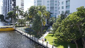 Ein Hotel am Wasser mit Wassertaxi-Service, Palmen und modernen Gebäuden im Hintergrund.