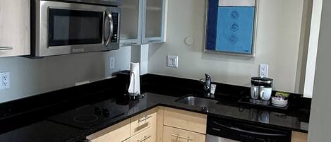 Una cocina moderna con electrodomésticos de acero inoxidable, armarios de madera y suelo de baldosas.