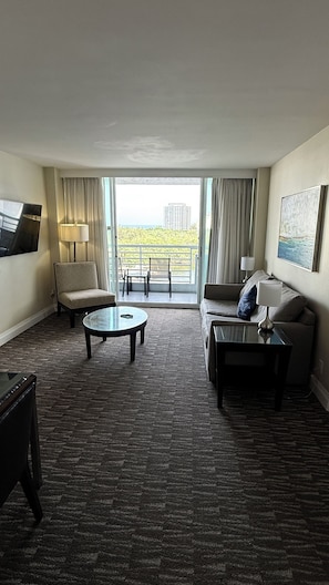 Ein Hotelzimmer mit Sofa, Sessel, Couchtisch und Fernseher.