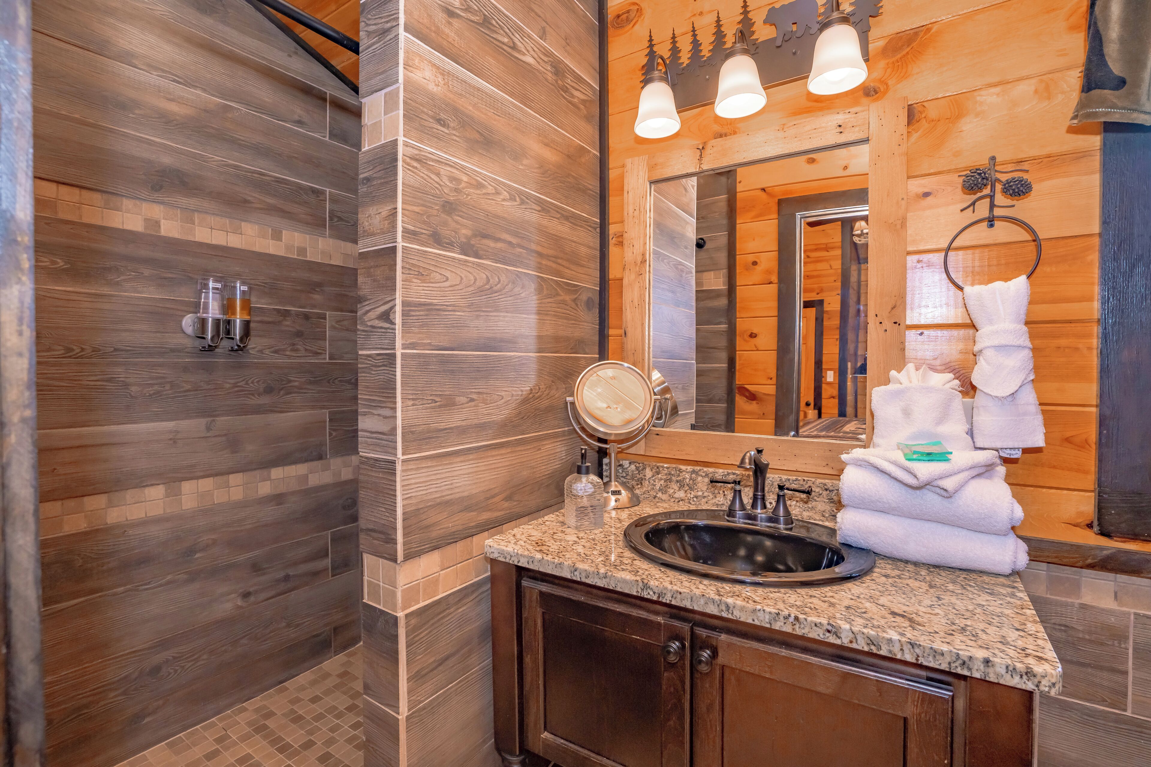 A bathroom with wooden walls, a granite countertop, a sink, a mirror, and a towel rack.