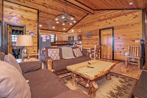 Ein Holzblockhaus-Interieur mit einer Couch, einem Couchtisch und einer Küchenzeile.