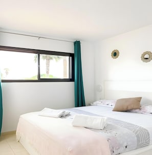 A bedroom with a bed, a window, and a view of greenery outside. - B-Rent El Royal Corralejo: Comfort and Style in a 1-Bedroom Apartment (Corralejo)