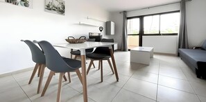A modern living room with a dining area, a sofa, a TV, and a balcony with a view. - B-Rent El Royal Corralejo: Comfort and Style in a 1-Bedroom Apartment (Corralejo)