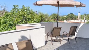 A balcony with two chairs, a table, and a large umbrella.
