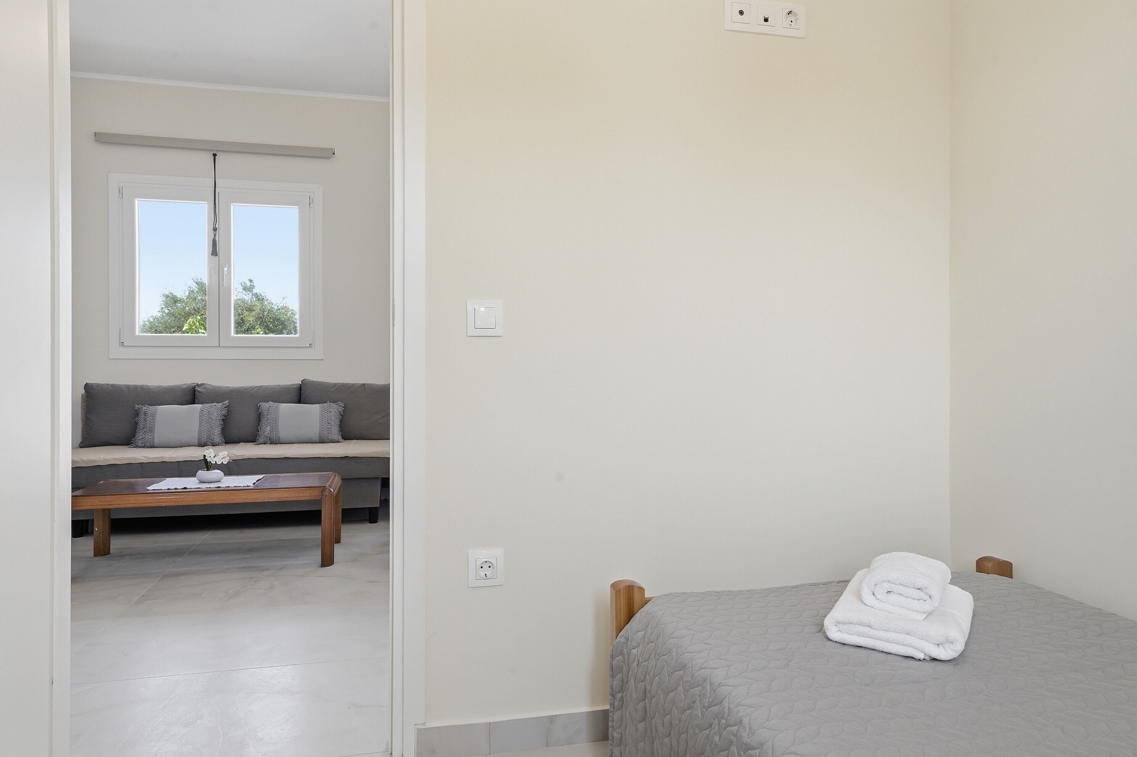 Een kamer met een bed, een slaapbank, een raam en een tafel.