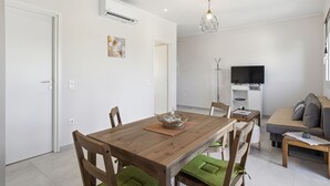 A dining area with a wooden table, chairs, and a TV in the background.