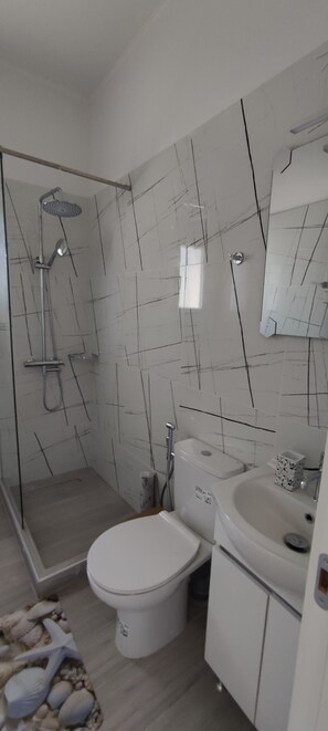 A bathroom with a shower, toilet, sink, and a mirror. - Elaia Pearl Apartment with Sea, Dune & Lake Views, Wi-Fi and Air Conditioning (Linia)