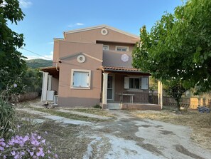A two-story house with a balcony, a small porch, and a garden area. - Elaia Pearl Apartment with Sea, Dune & Lake Views, Wi-Fi and Air Conditioning (Linia)
