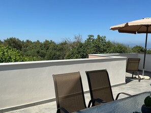 A rooftop terrace with two chairs, a table, and an umbrella.