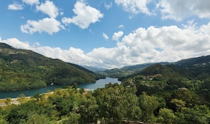 Un paysage montagneux avec un lac, une forêt dense et quelques bâtiments dispersés.