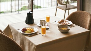 A breakfast table with plates of food, glasses of orange juice, and a coffee pot.