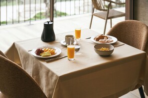 A breakfast table with plates of food, glasses of orange juice, and a coffee pot. - Hotel Aquafalls (Caniçada)