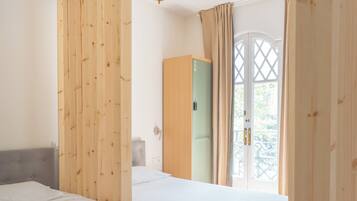 A room with two beds, a wardrobe, and a door leading to an outdoor area.