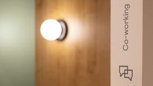 A wooden door with a circular light fixture and a vertical sign with the text 'Co-working.' - Casa Nido Diagonal (Barcelona)