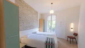 A bedroom with a bed, a chair, a wardrobe, and a window with a view. - Casa Nido Diagonal (Barcelona)