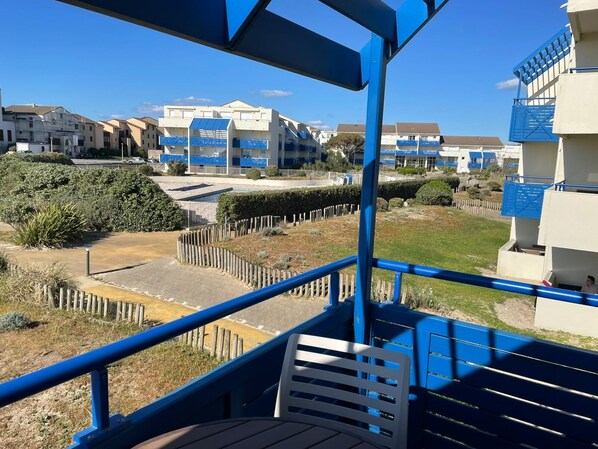 Un balcon donnant sur des immeubles d’habitation, une zone délimitée par une clôture et un ciel dégagé.