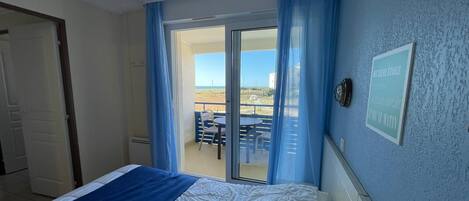 Un dormitorio con cama, vistas al balcón exterior y un cartel enmarcado en la pared.