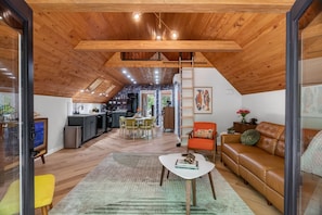 A spacious loft with a wooden ceiling, a dining area, a kitchen, and a living room with a leather sofa.