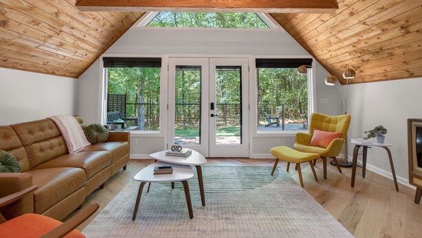 A cozy room with a sloped ceiling, a brown leather sofa, a yellow armchair, and a small white table.