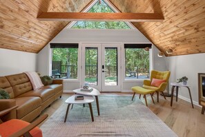 A cozy room with a sloped ceiling, a brown leather sofa, a yellow armchair, and a small white table.