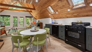 A modern kitchen with a wooden ceiling, a round dining table with chairs, and a large oven.