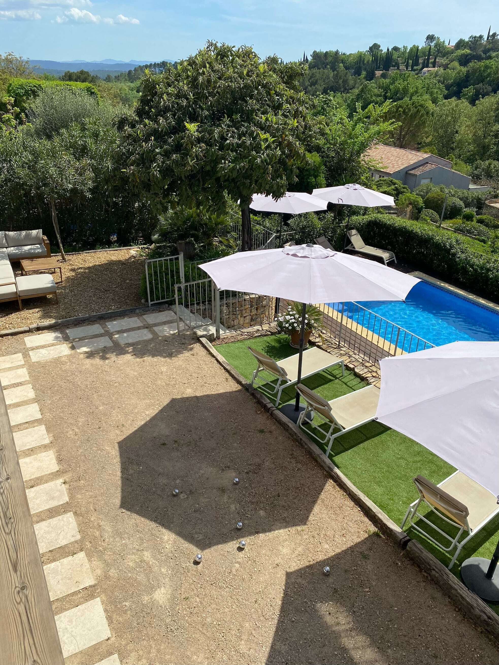 Um quintal com piscina, móveis de exterior e vista da paisagem ao redor.