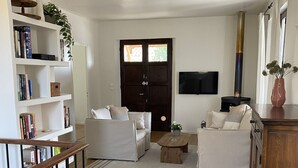 Ein Wohnzimmer mit einer Sofagarnitur, einem Couchtisch, einem Bücherregal, einem Fernseher und einem Kamin.