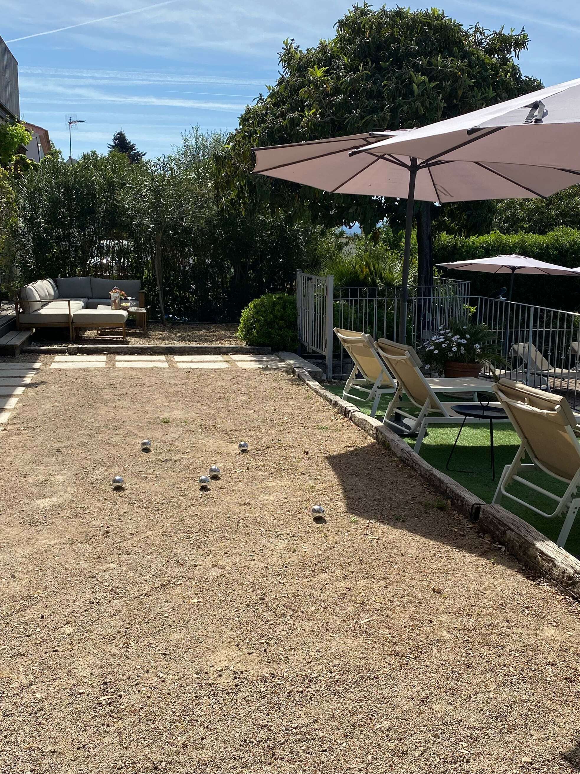 Un espace extérieur aménagé avec des sièges, un jeu de plein air, un canapé et des parasols.