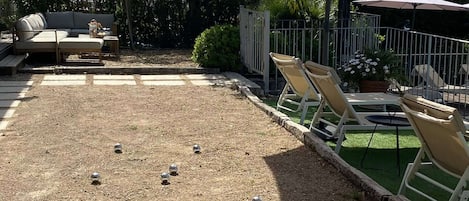 Un espace extérieur aménagé avec des sièges, un jeu de plein air, un canapé et des parasols.