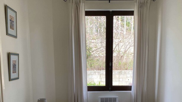 Ein Zimmer mit zwei Betten, einem kleinen Tisch mit Lampe, einer Zimmerpflanze und einem Fenster mit Vorhängen.