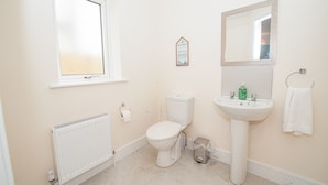 Een badkamer met toilet, wastafel, spiegel, raam en radiator.