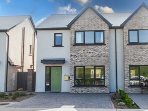 A modern residential building with a brick facade, a green door, and a small garden area. - Dunmore East Sunrise Meadows (Dunmore East)