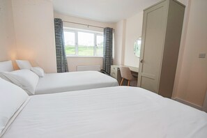 A bedroom with two beds, a desk, and a window with curtains. - Dunmore East Sunrise Meadows (Dunmore East)
