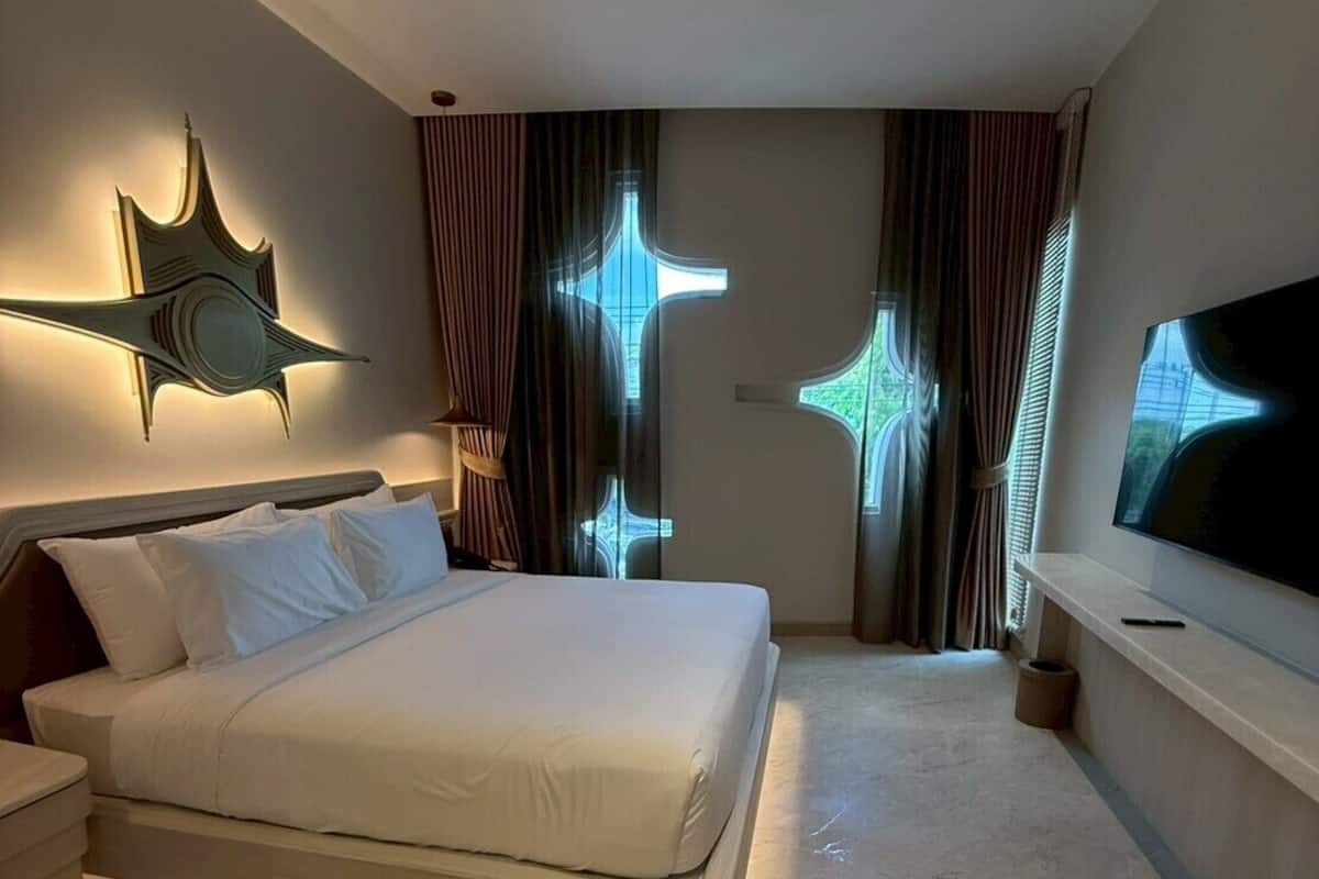 A modern hotel room with a large bed, a flat-screen TV, and a unique star-shaped light fixture.
