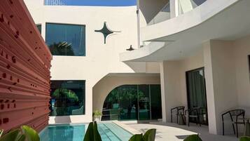 Un edificio moderno con piscina, zona de estar exterior y entrada de cristal.