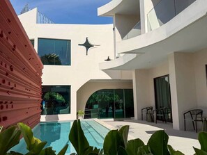 A modern building with a pool, outdoor seating, and a glass entrance. - The Rachata Ayothaya (Ayutthaya)