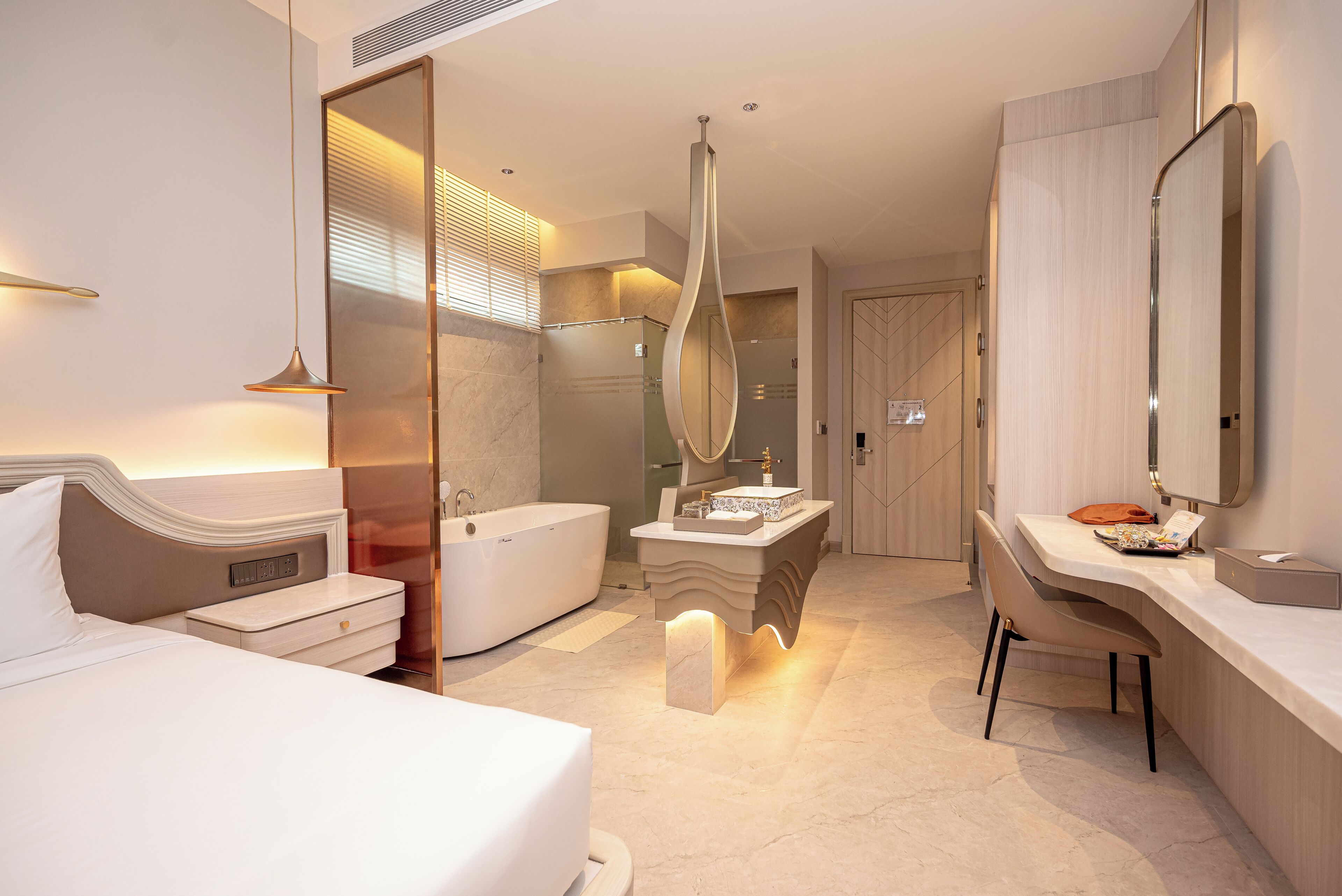 Une chambre d’hôtel moderne équipée d’un lit, d’une baignoire, d’une coiffeuse avec un miroir et d’un bureau.
