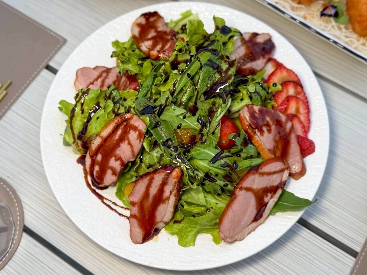 Un plato de comida con verduras, fresas y carne.
