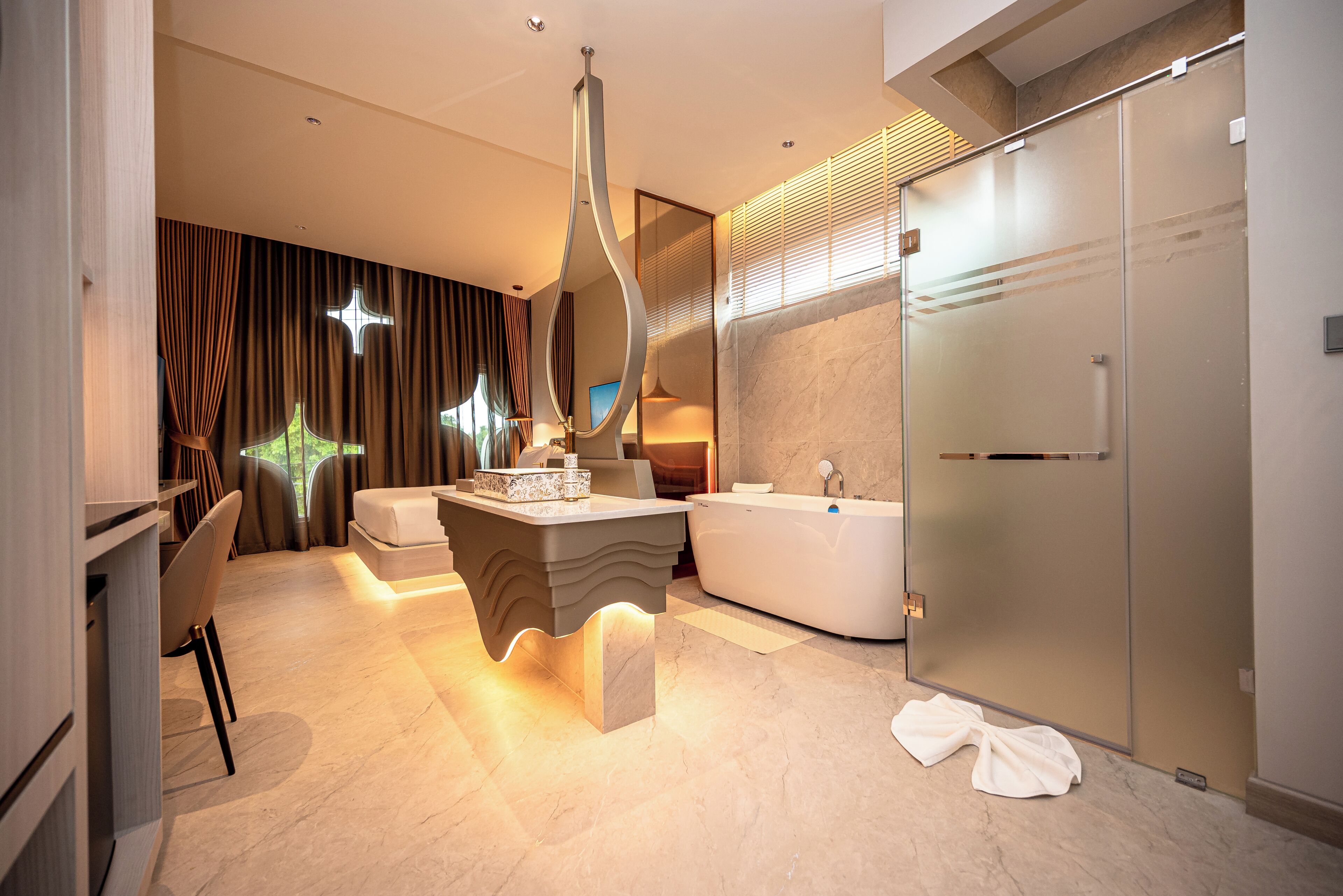 Un baño moderno con una bañera independiente, un tocador con una lámpara original y un espejo grande.