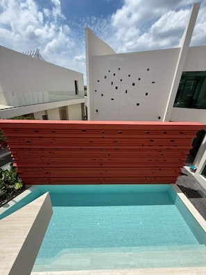 A modern building with a pool, a red wall, and a clear blue sky. - The Rachata Ayothaya (Ayutthaya)