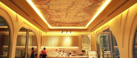 A restaurant with a unique ceiling design, seating area, and a counter.
