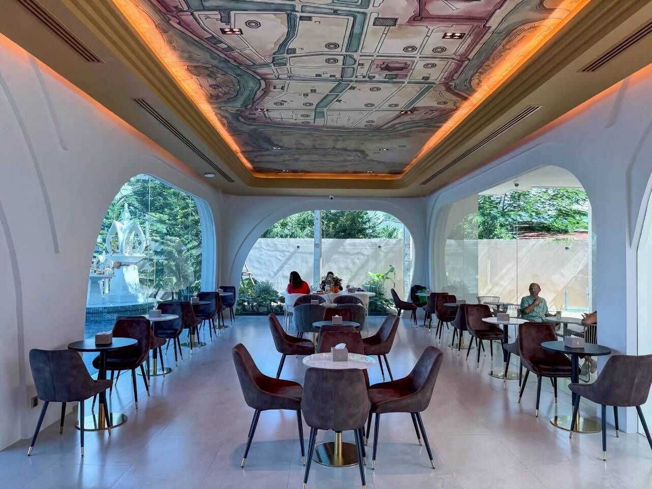 A modern dining area with round tables and chairs, large windows, and a unique ceiling design.