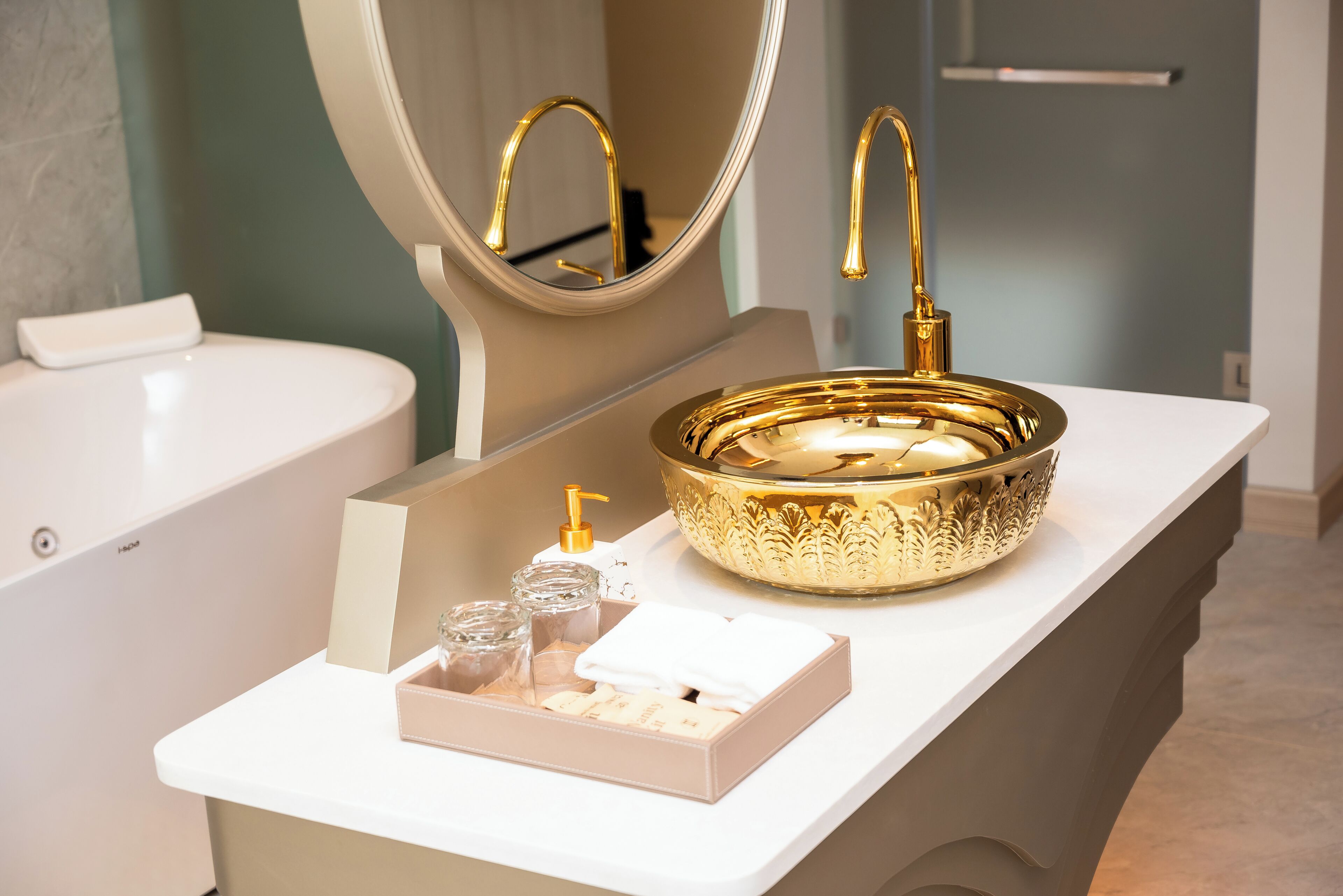 A bathroom with a gold sink, a mirror, and a white countertop.