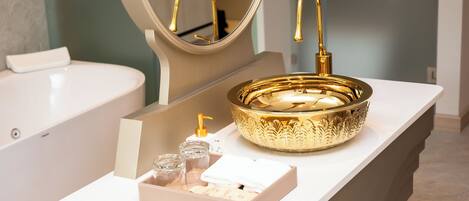 A bathroom with a gold sink, a mirror, and a white countertop.